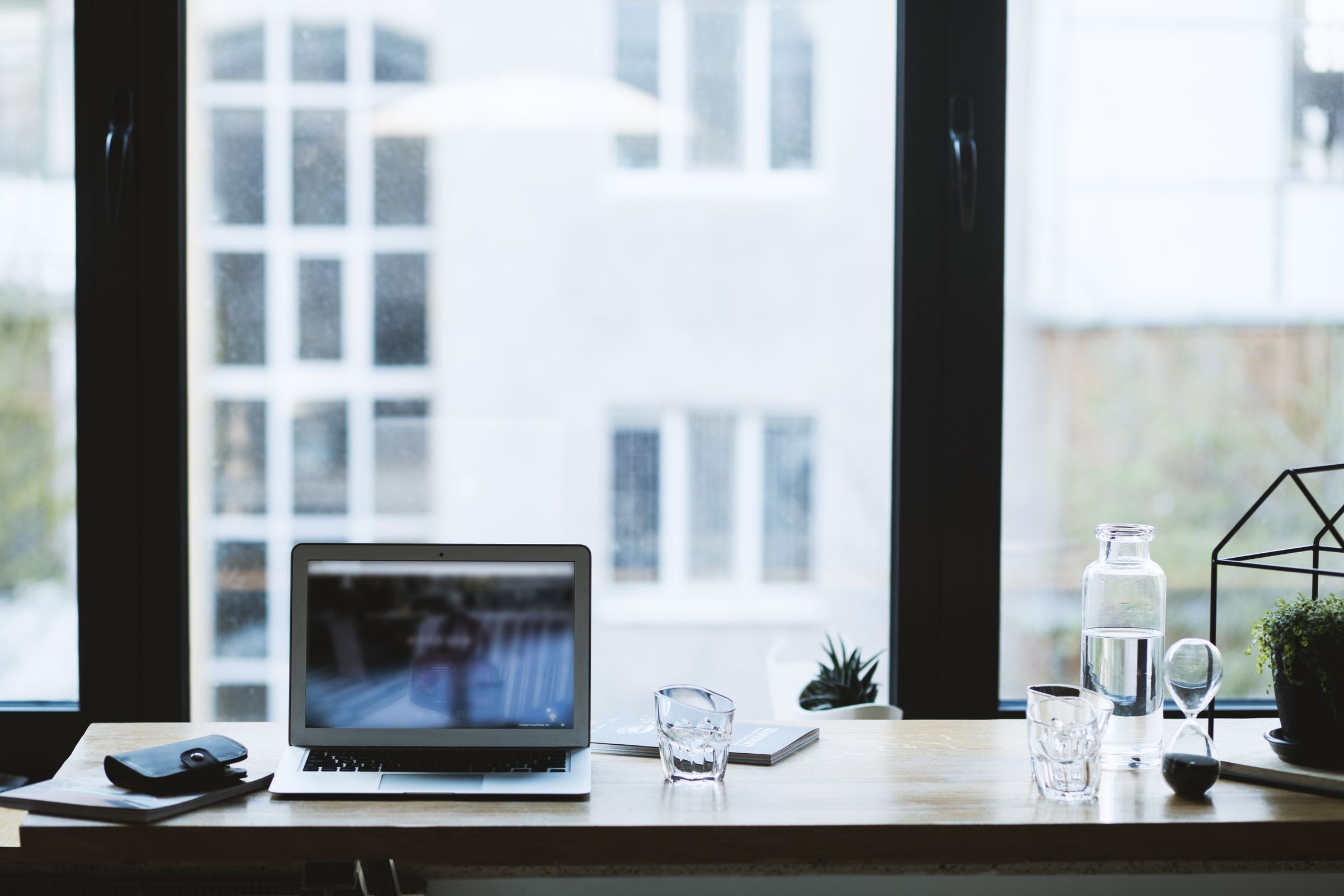 Ledgers and a laptop on a desk by a canal-side window in an Amsterdam office