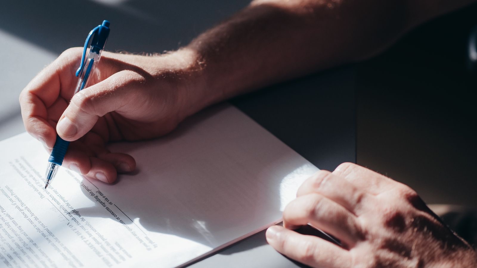 A pen resting on signed documents on a desk